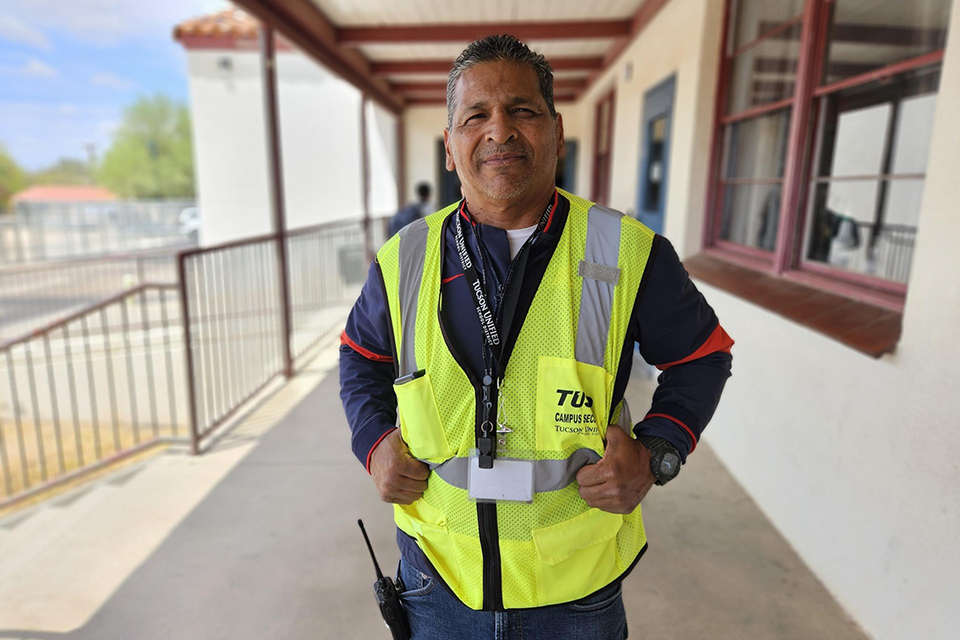 A man in a yellow safety vest stands with his hands on his hips