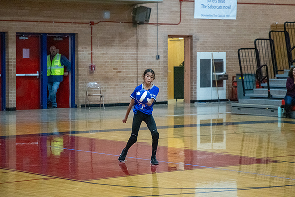 A girl serves the volleyball over the net