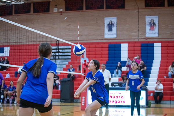 A girl sets the volleyball over the net