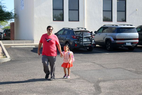 A dad walks with his young daughter to school